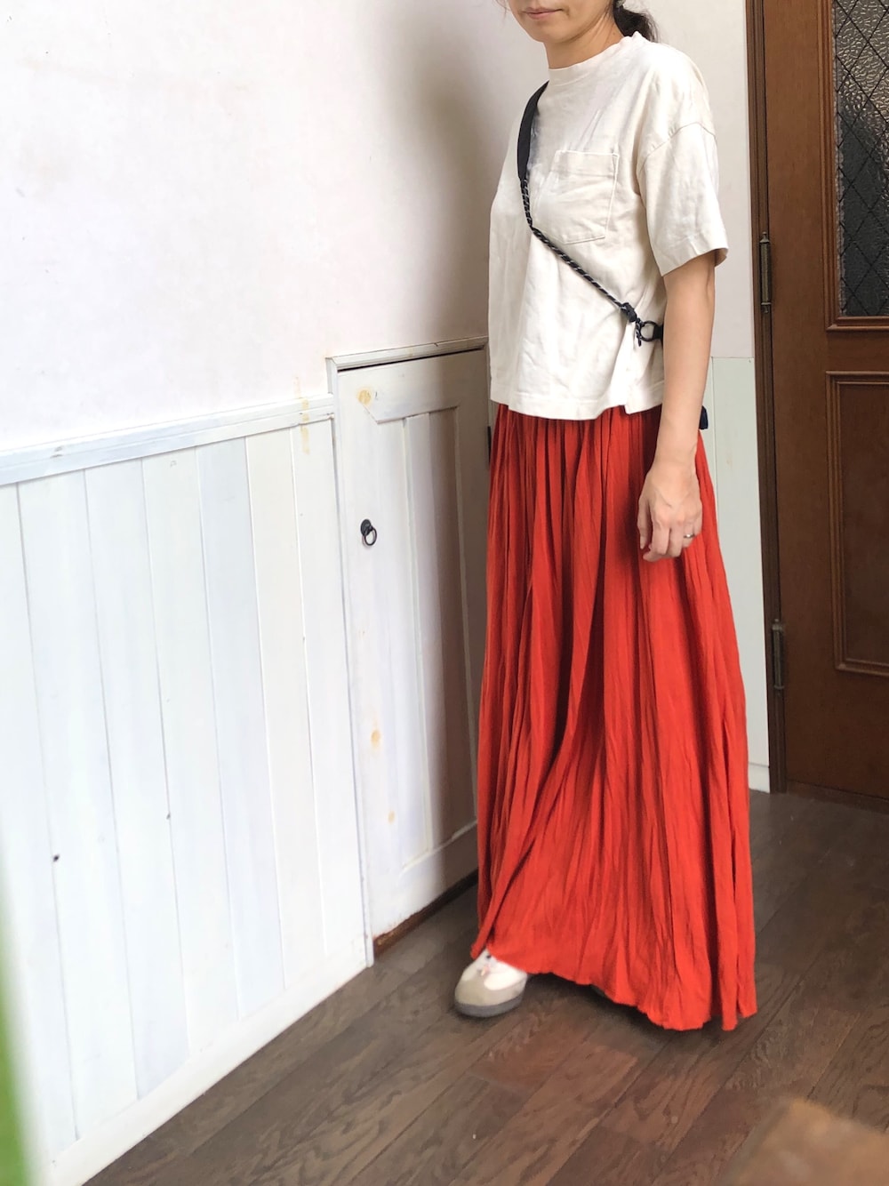 ブラウン系のスカート、ベージュ系のTシャツ/カットソー、ブルー系のメッセンジャーバッグを着用したレディースの夏コーディネートの1枚目の写真