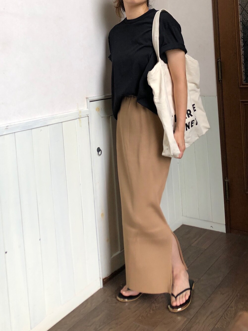 ベージュ系のスカート、ブラック系のTシャツ/カットソー、ホワイト系のトートバッグを着用したレディースの夏コーディネートの1枚目の写真