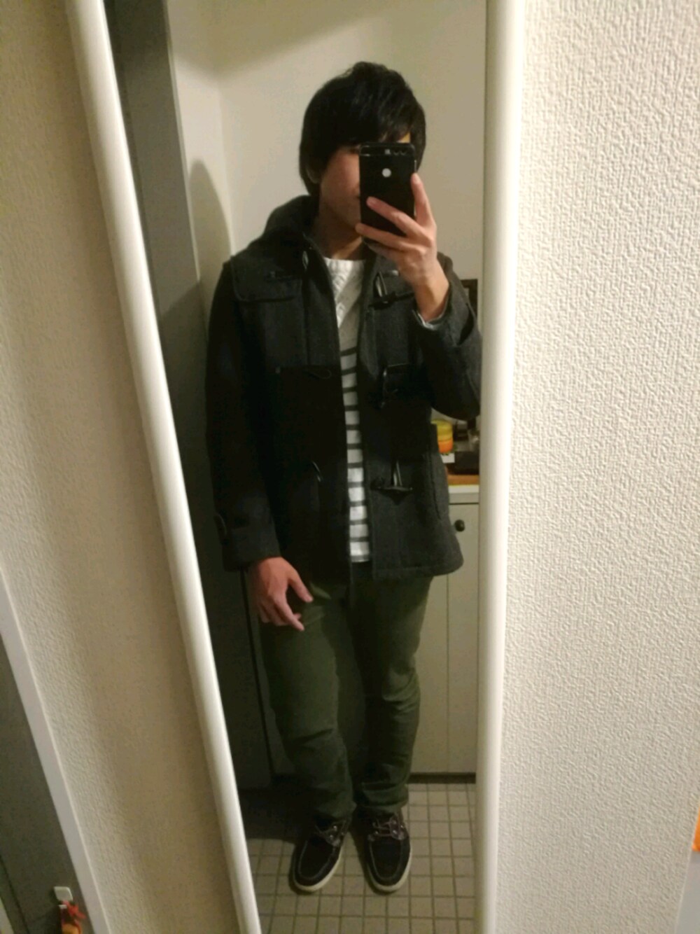 グレー系のダッフルコート、ホワイト系のニット/セーター、ブラック系のアナログ腕時計を着用したメンズの冬コーディネートの1枚目の写真