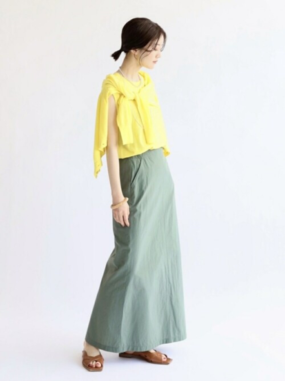 イエロー系のカーディガン/ボレロ、イエロー系のニット/セーター、グリーン系のスカートを着用したレディースの夏コーディネートの1枚目の写真