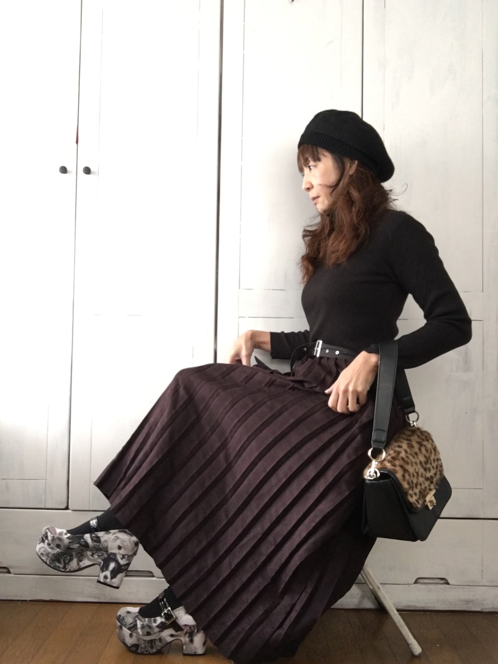 ブラック系のパンプス、グレー系のスカート、ブラック系のニット/セーターを着用したレディースの冬コーディネートの1枚目の写真