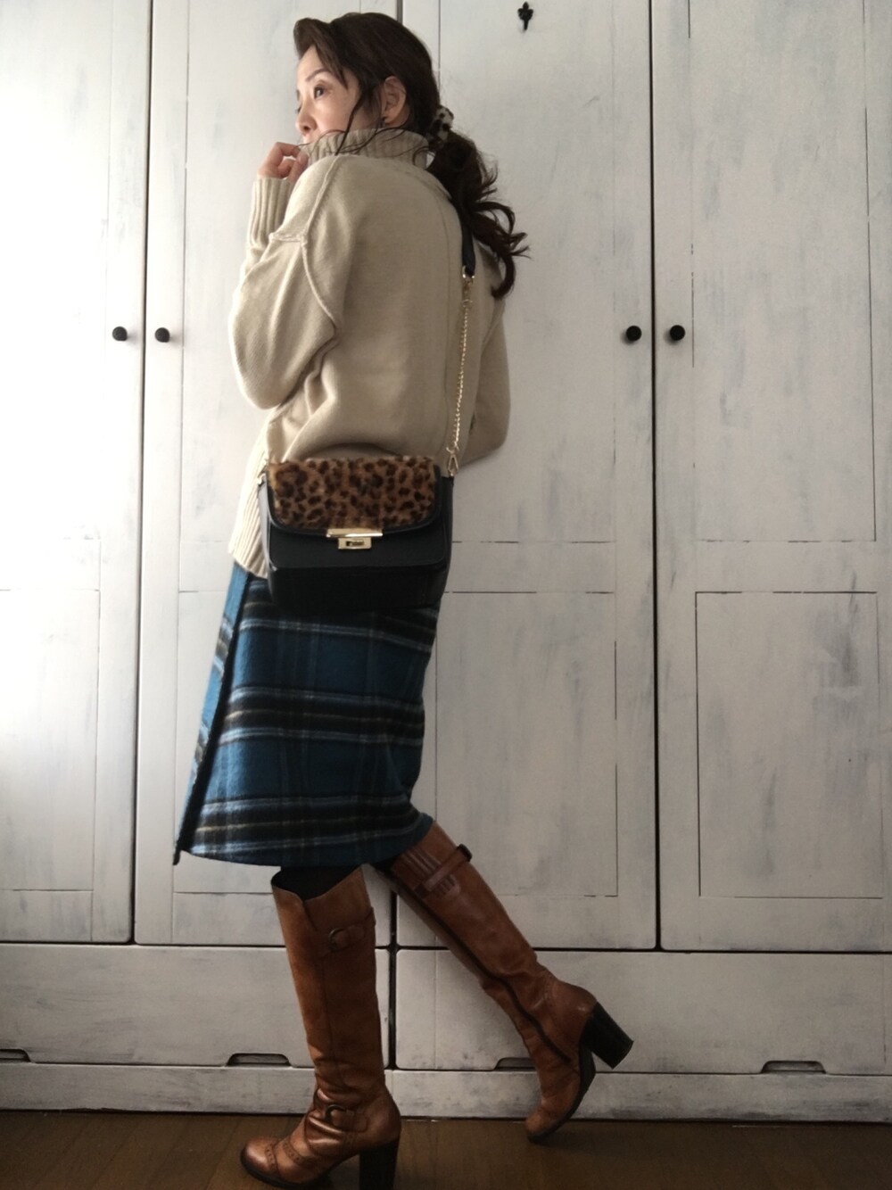 ベージュ系のニット/セーター、ブラック系のバッグ、グリーン系のスカートを着用したレディースの冬コーディネートの1枚目の写真