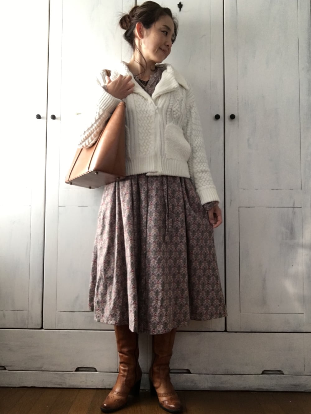 ホワイト系のライダースジャケット、ピンク系のワンピース、ブラウン系のバッグを着用したレディースの冬コーディネートの1枚目の写真