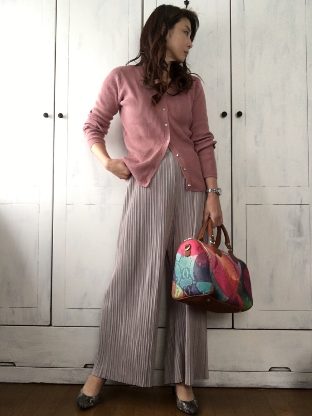 ピンク系のニット/セーター、ベージュ系のその他パンツ、レッド系のハンドバッグを着用したレディースの春コーディネートの1枚目の写真