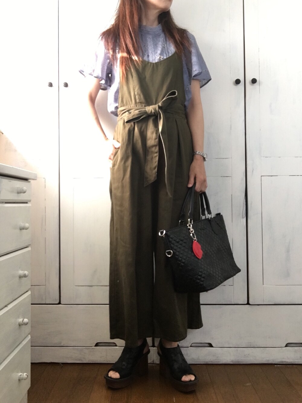 ホワイト系のトップス、グリーン系のサロペット/オーバーオール、ブラック系のハンドバッグを着用したレディースの春コーディネートの1枚目の写真