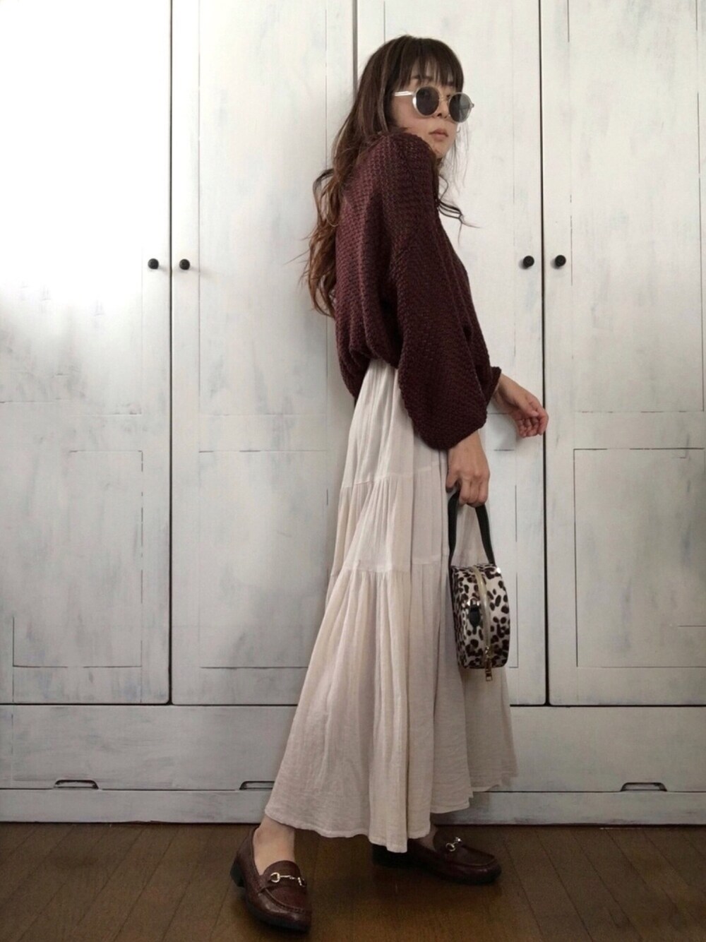 ベージュ系のバッグ、ブラウン系のニット/セーター、ベージュ系のワンピースを着用したレディースの秋コーディネートの1枚目の写真
