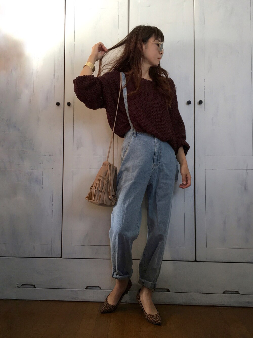 ブラウン系のニット/セーター、ブルー系のデニムパンツ、ベージュ系のバッグを着用したレディースの秋コーディネートの1枚目の写真