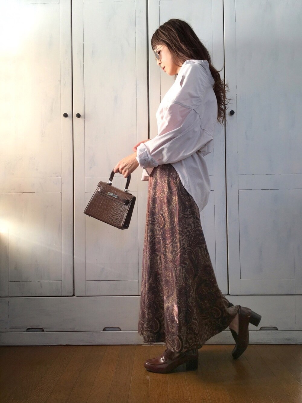 ベージュ系のTシャツ/カットソー、ブラウン系のスカート、ブラウン系のローファーを着用したレディースの秋コーディネートの1枚目の写真