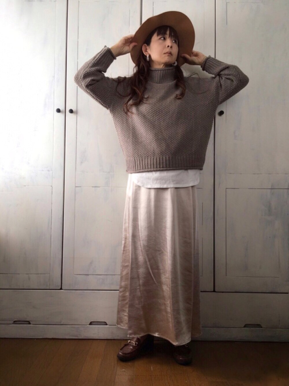 ブラウン系のニット/セーター、ホワイト系のTシャツ/カットソー、ホワイト系のスカートを着用したレディースの秋コーディネートの1枚目の写真