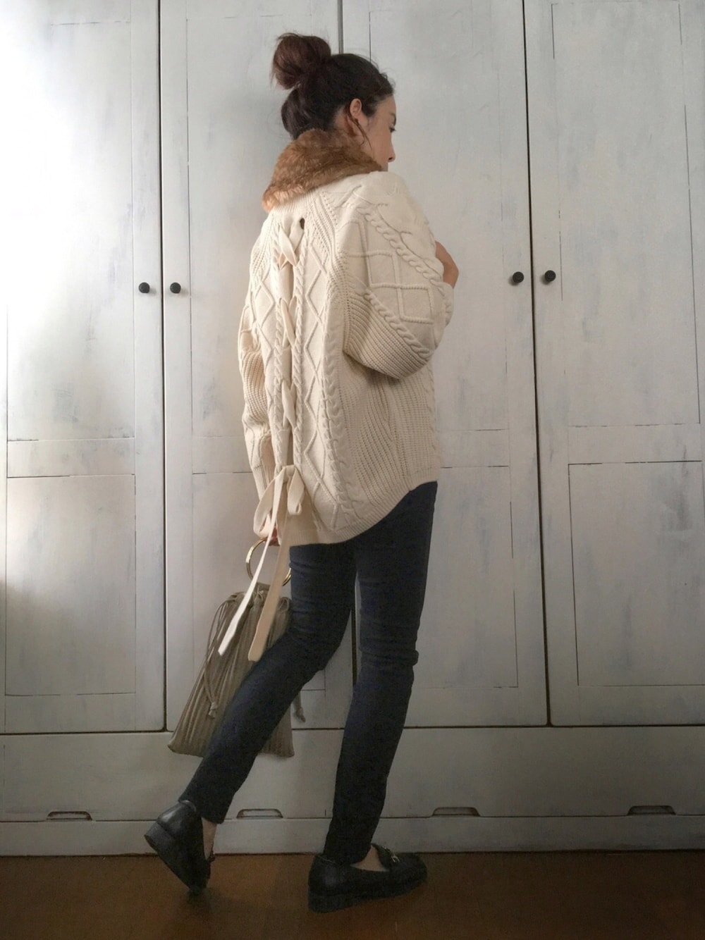 ホワイト系のニット/セーター、ブラック系のパンツ、グリーン系のトートバッグを着用したレディースの秋コーディネートの1枚目の写真