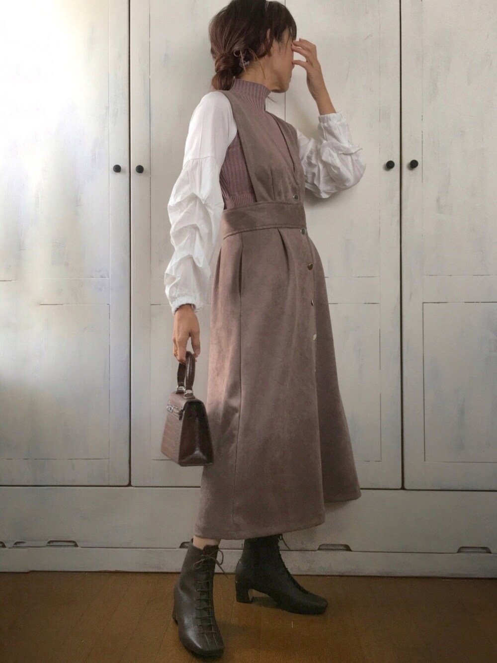 ブラウン系のシャツ/ブラウス、ブラウン系のジャンパースカート、ブラウン系のハンドバッグを着用したレディースの秋コーディネートの1枚目の写真