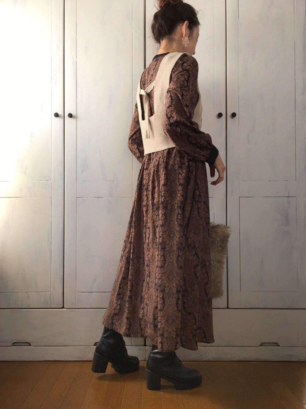 ベージュ系のベスト、ブラック系のワンピース、ベージュ系のトートバッグを着用したレディースの冬コーディネートの1枚目の写真