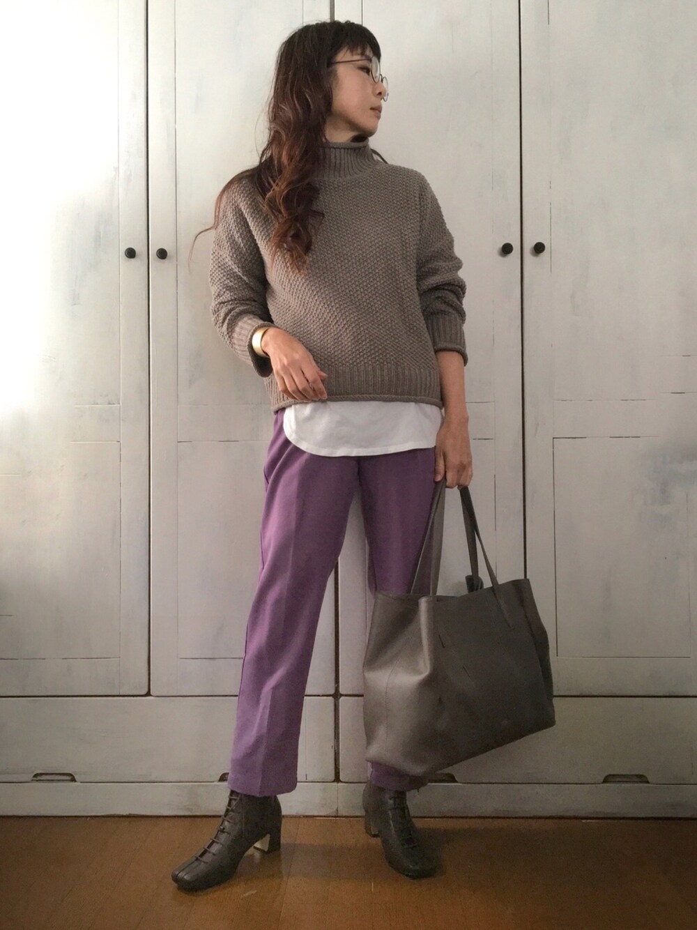 ブラウン系のニット/セーター、ホワイト系のTシャツ/カットソー、パープル系のスラックスを着用したレディースの冬コーディネートの1枚目の写真