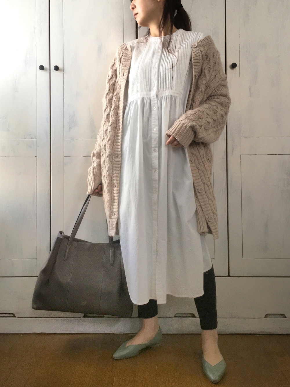 ベージュ系のカーディガン/ボレロ、ホワイト系のワンピース、グレー系のトートバッグを着用したレディースの冬コーディネートの1枚目の写真