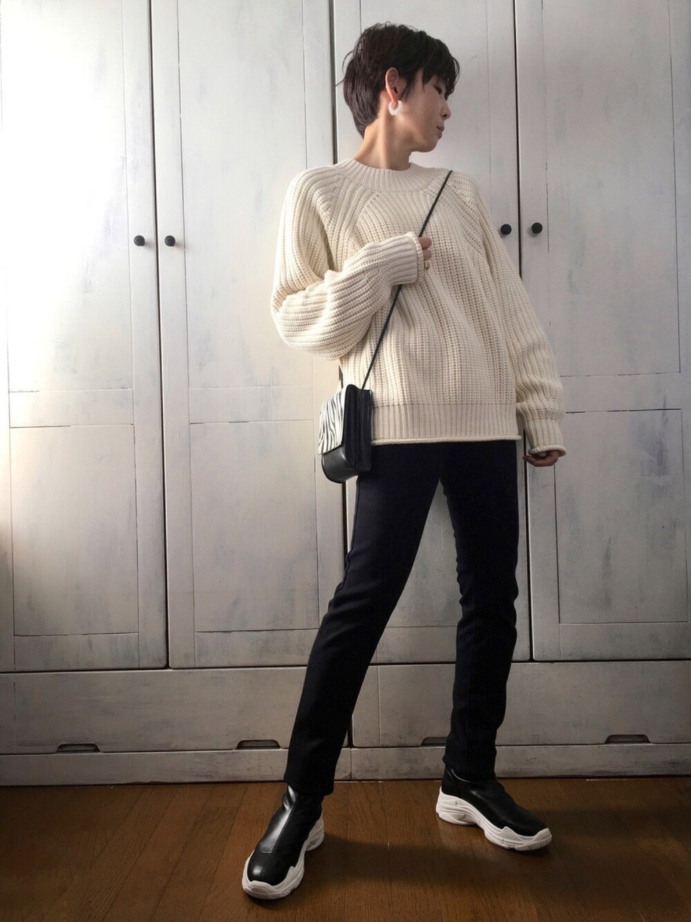 ホワイト系のニット/セーター、ブラック系のパンツ、ブラック系のショルダーバッグを着用したレディースの冬コーディネートの1枚目の写真