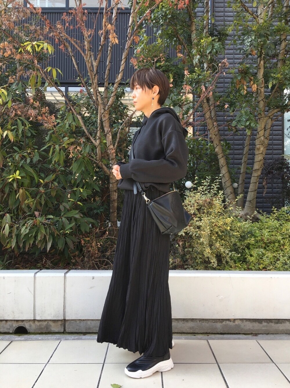 ブラック系のワンピース、ブラック系のハンドバッグ、ブラック系のブーツを着用したレディースの冬コーディネートの1枚目の写真