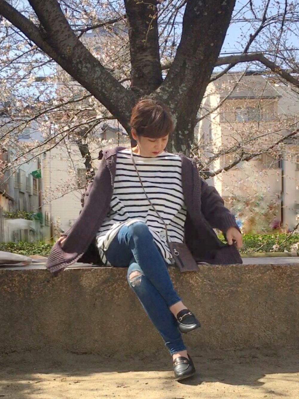 グレー系のニット/セーター、ブルー系のTシャツ/カットソー、グリーン系のショルダーバッグを着用したレディースの春コーディネートの1枚目の写真