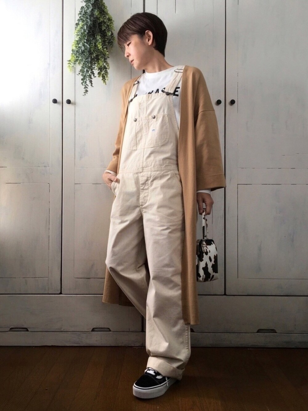 ベージュ系のカーディガン/ボレロ、ホワイト系のTシャツ/カットソー、ホワイト系のサロペット/オーバーオールを着用したレディースの春コーディネートの1枚目の写真