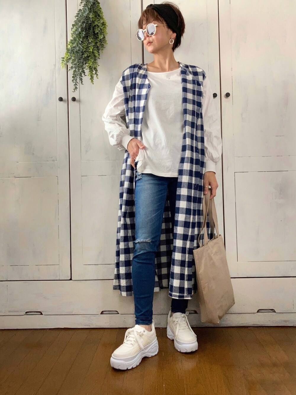 ブルー系のワンピース、ブラウン系のベスト、ブルー系のデニムパンツを着用したレディースの春コーディネートの1枚目の写真