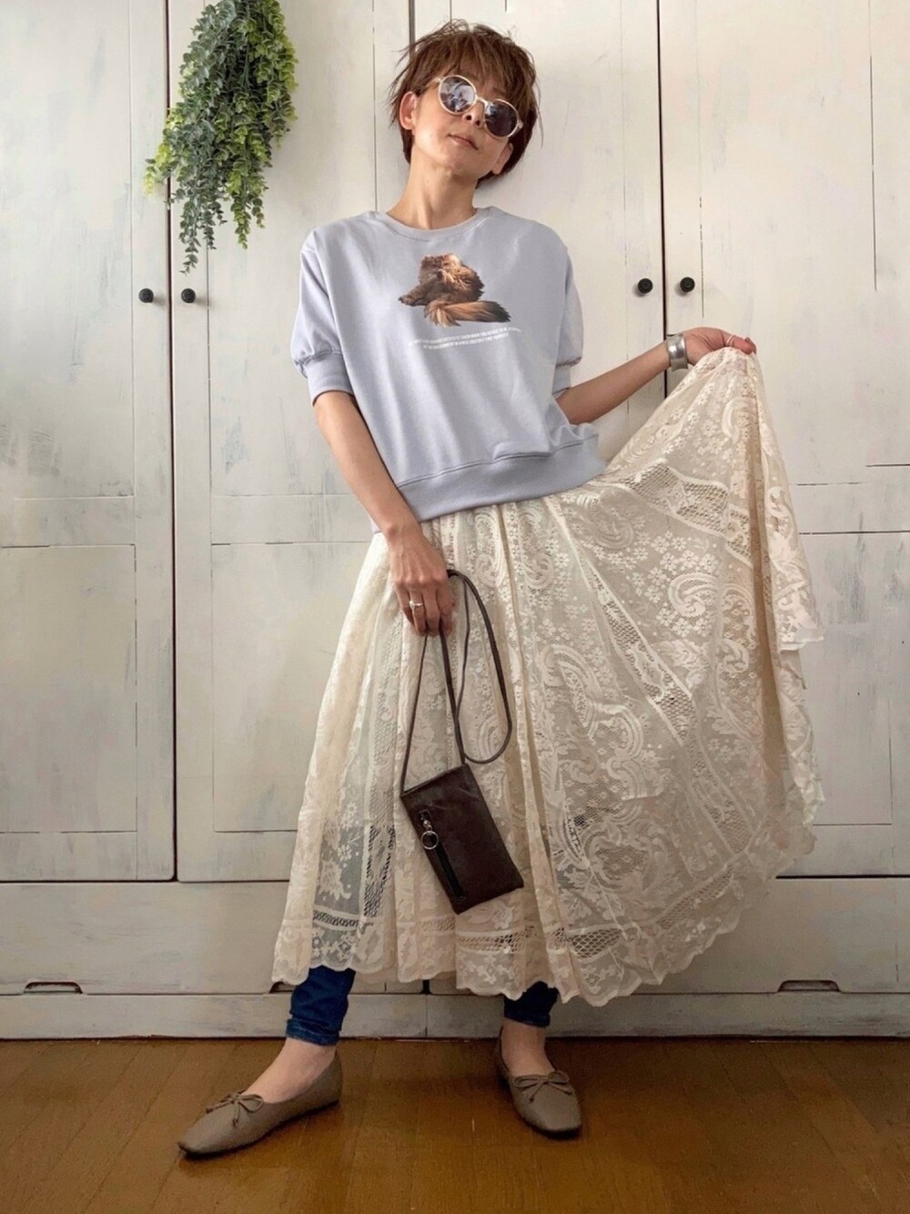 ブルー系のスウェット、ホワイト系のスカート、ブルー系のデニムパンツを着用したレディースの春コーディネートの1枚目の写真