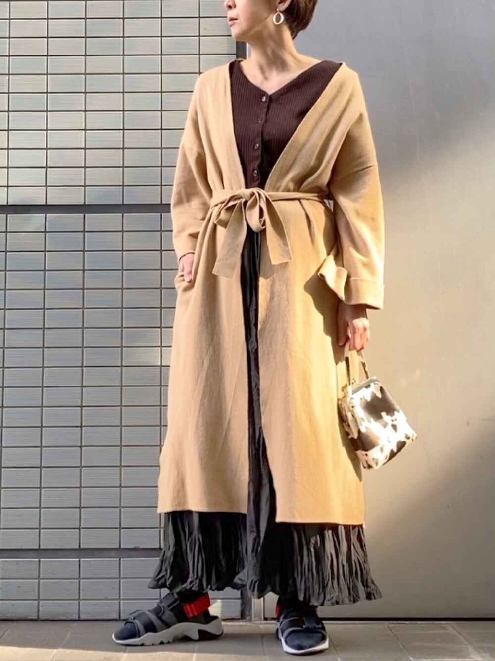 ベージュ系のカーディガン/ボレロ、ブラウン系のニット/セーター、グレー系のスカートを着用したレディースの春コーディネートの1枚目の写真