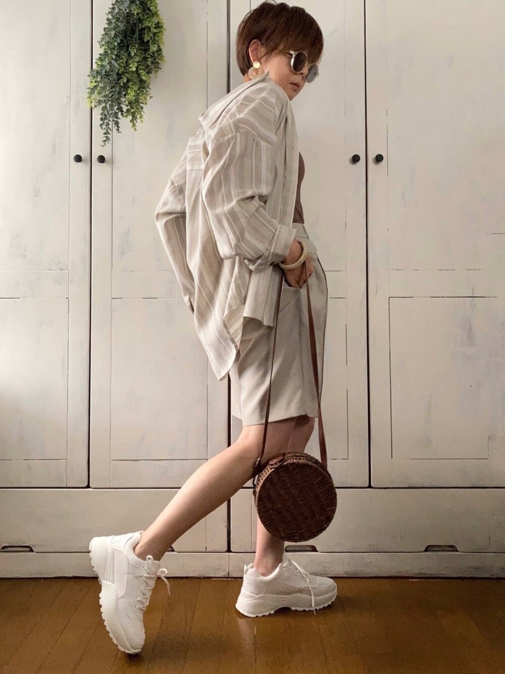 ベージュ系のシャツ/ブラウス、ブラウン系のタンクトップ、ベージュ系のパンツを着用したレディースの春コーディネートの1枚目の写真