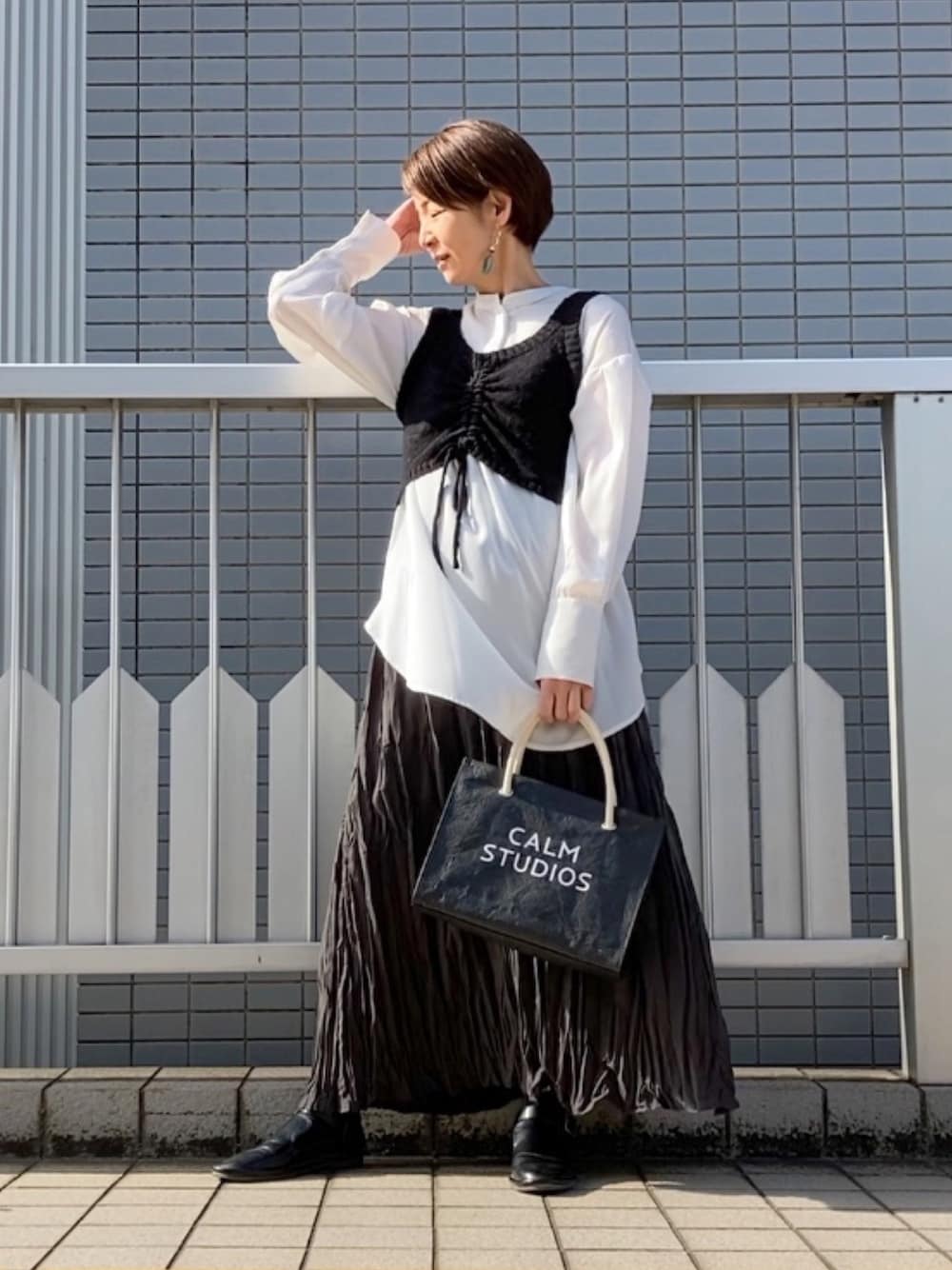 ブラック系のベスト、ホワイト系のシャツ/ブラウス、ブラック系のトートバッグを着用したレディースの春コーディネートの1枚目の写真