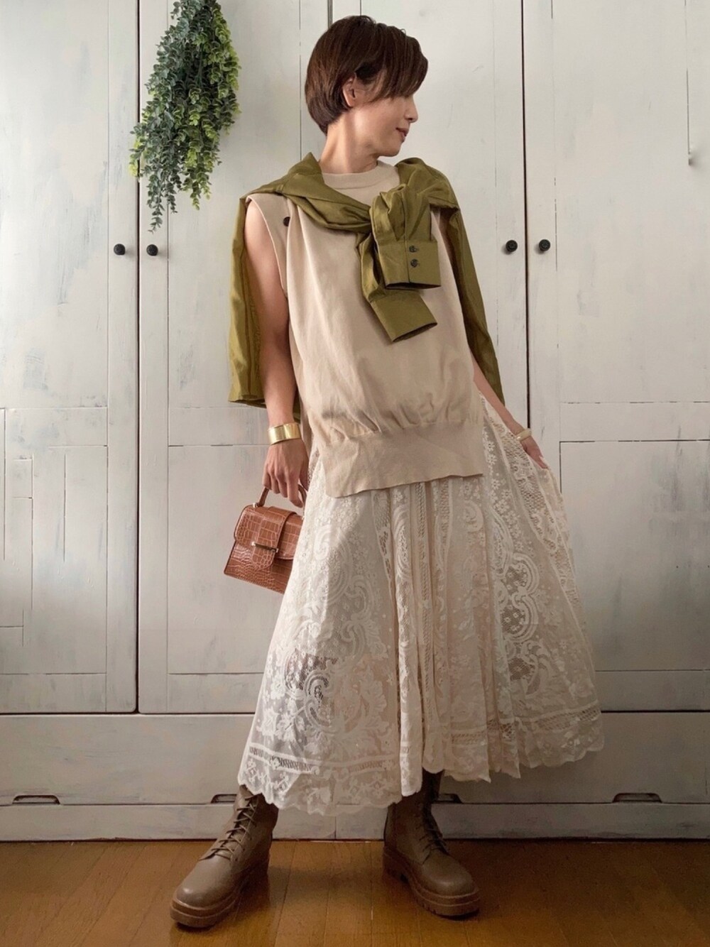 グリーン系のシャツ/ブラウス、ベージュ系のニット/セーター、ホワイト系のスカートを着用したレディースの春コーディネートの1枚目の写真