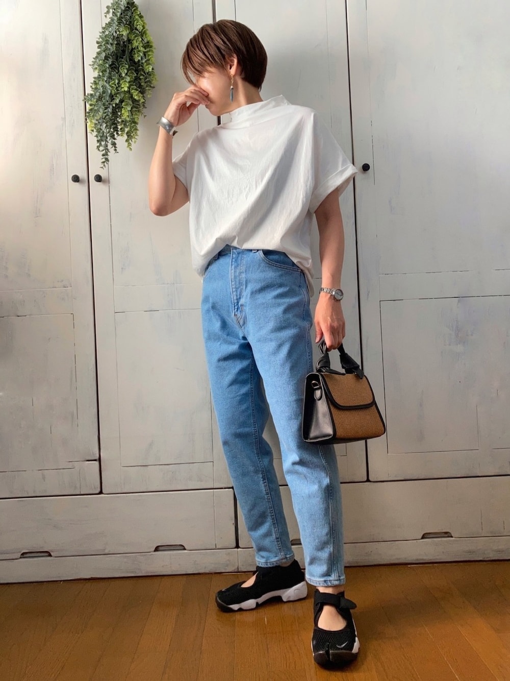 ホワイト系のTシャツ/カットソー、ブルー系のデニムパンツ、ベージュ系のハンドバッグを着用したレディースの夏コーディネートの1枚目の写真