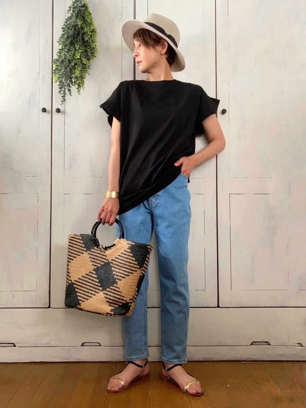 ブラック系のトートバッグ、ブラック系のTシャツ/カットソー、ブルー系のデニムパンツを着用したレディースの夏コーディネートの1枚目の写真
