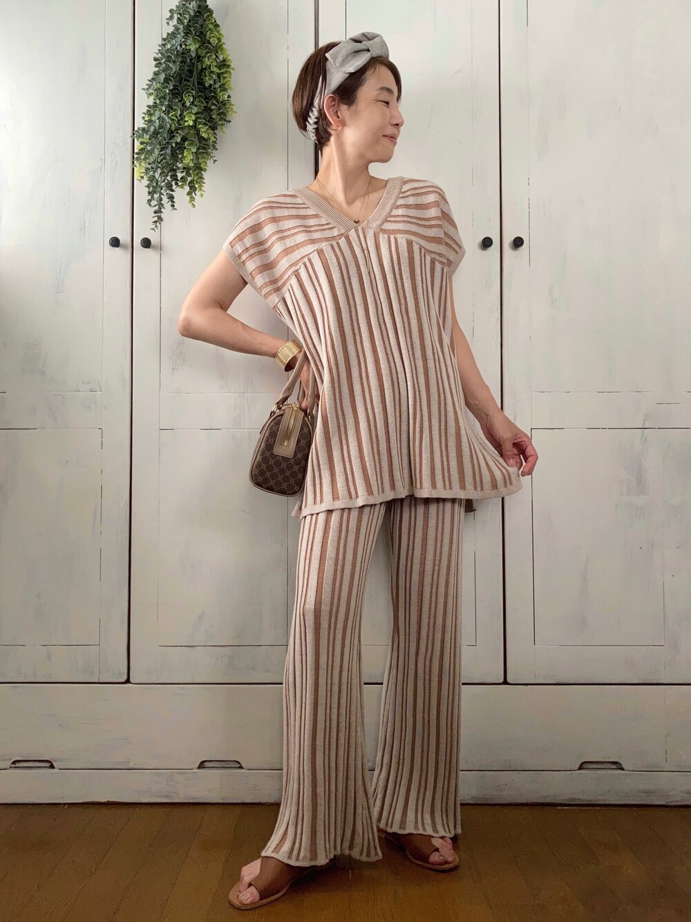 ブラウン系のニット/セーター、ブラウン系のその他パンツ、ブラウン系のボストンバッグを着用したレディースの夏コーディネートの1枚目の写真