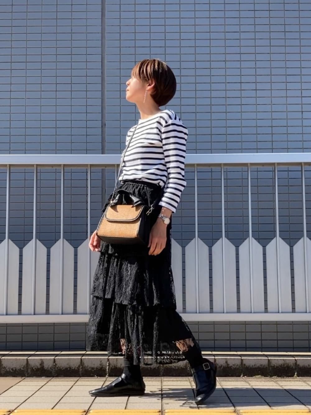ブラック系のスカート、ベージュ系のハンドバッグ、ブラック系のローファーを着用したレディースの夏コーディネートの1枚目の写真