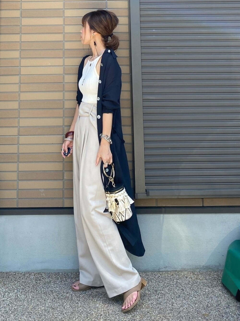 ホワイト系のキャミソール、ベージュ系のスラックス、ベージュ系のサンダルを着用したレディースの夏コーディネートの1枚目の写真