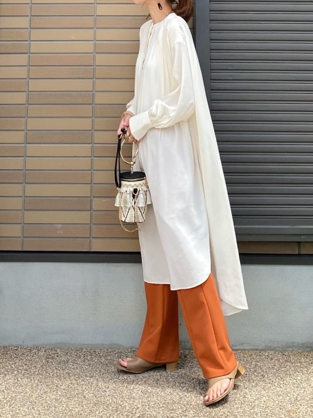 ホワイト系のワンピース、オレンジ系のスラックス、ベージュ系のサンダルを着用したレディースの夏コーディネートの1枚目の写真