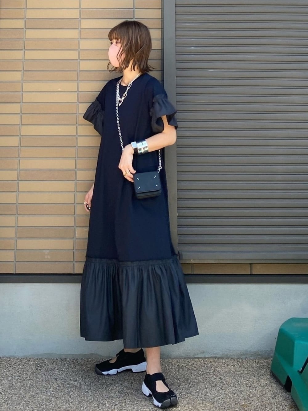 ブラック系のドレス、ブラック系のスニーカー、ブラック系のバッグを着用したレディースの春コーディネートの1枚目の写真