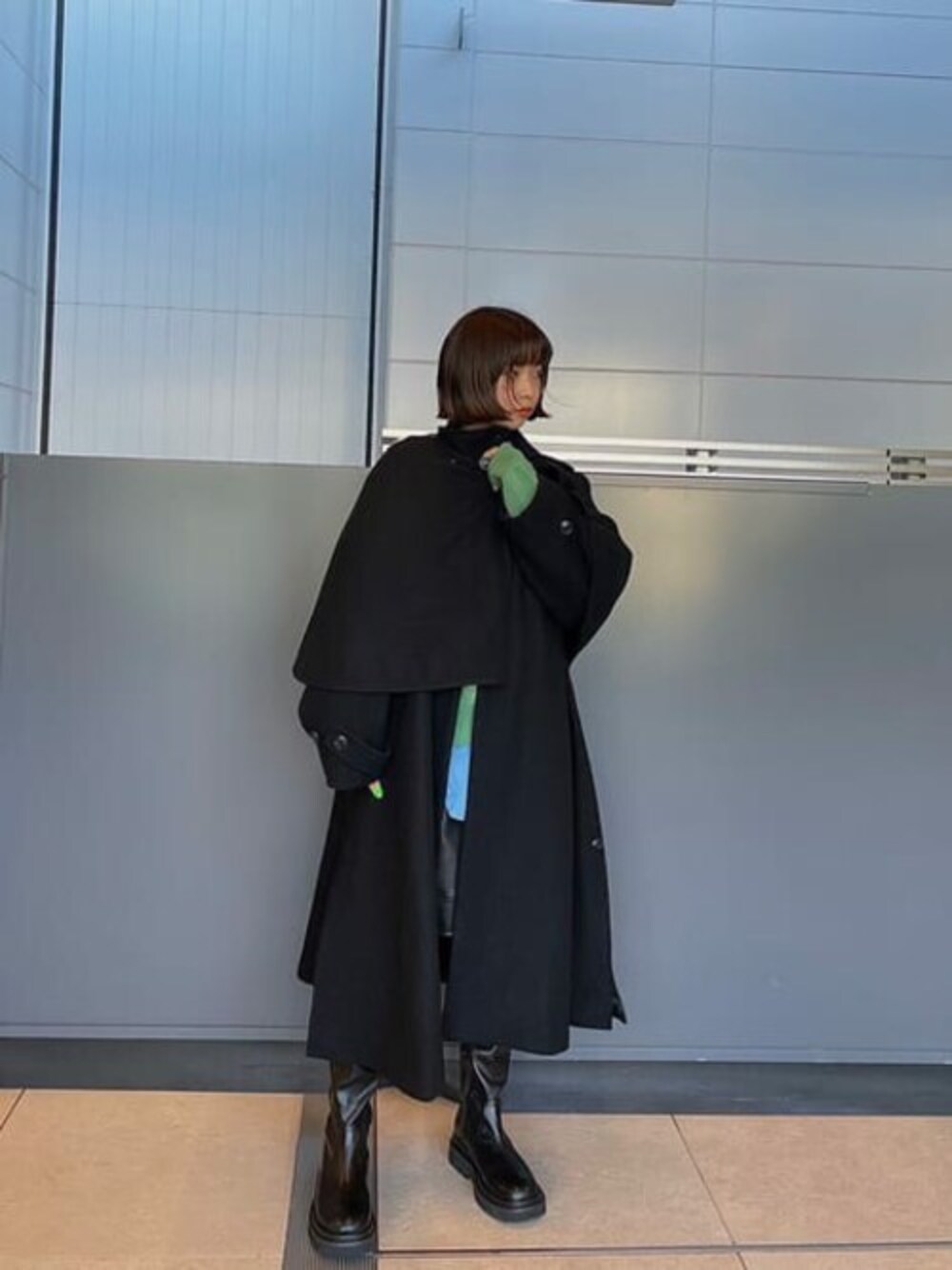 ブラック系のステンカラーコート、ブラック系のブーツ、ブルー系のシャツ/ブラウスを着用したレディースの秋コーディネートの1枚目の写真