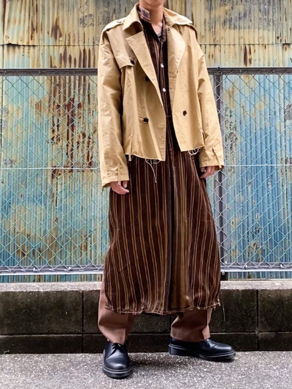 ブラウン系のシャツワンピース、ベージュ系のトレンチコート、ブラウン系のスラックスを着用したメンズの冬コーディネートの1枚目の写真