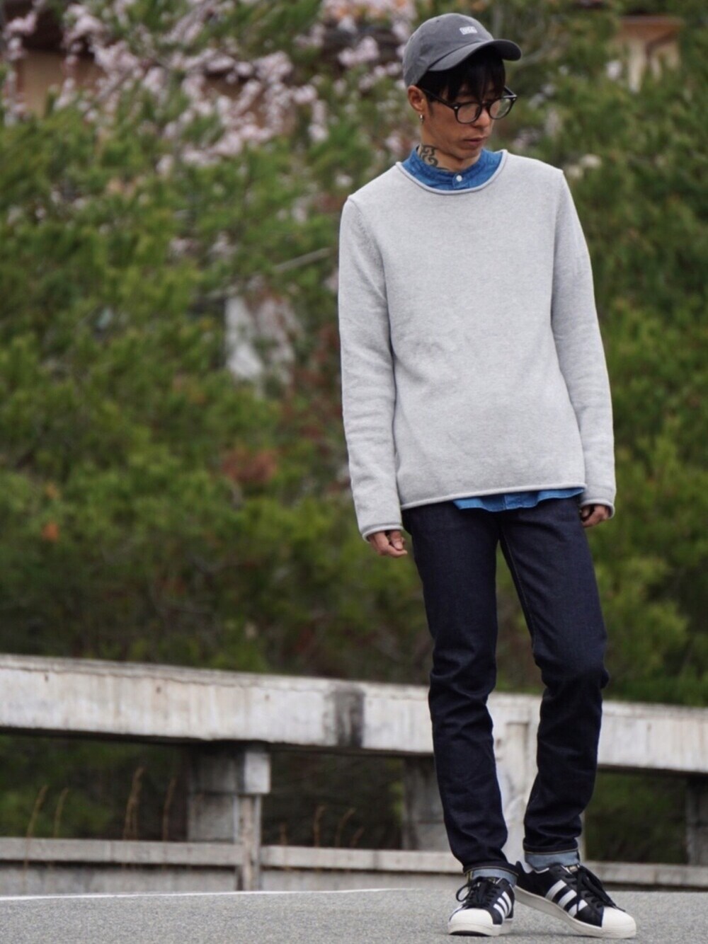 ブラック系のスニーカー、ブルー系のデニムパンツ、グレー系のニット/セーターを着用したメンズの春コーディネートの1枚目の写真