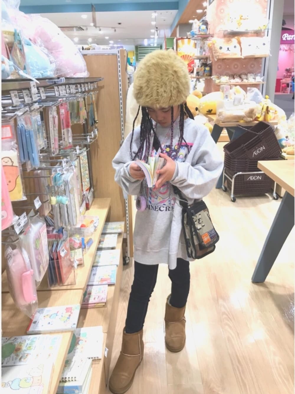 グレー系のスウェット、ベージュ系のショルダーバッグ、ブルー系のデニムパンツを着用したキッズの冬コーディネートの1枚目の写真