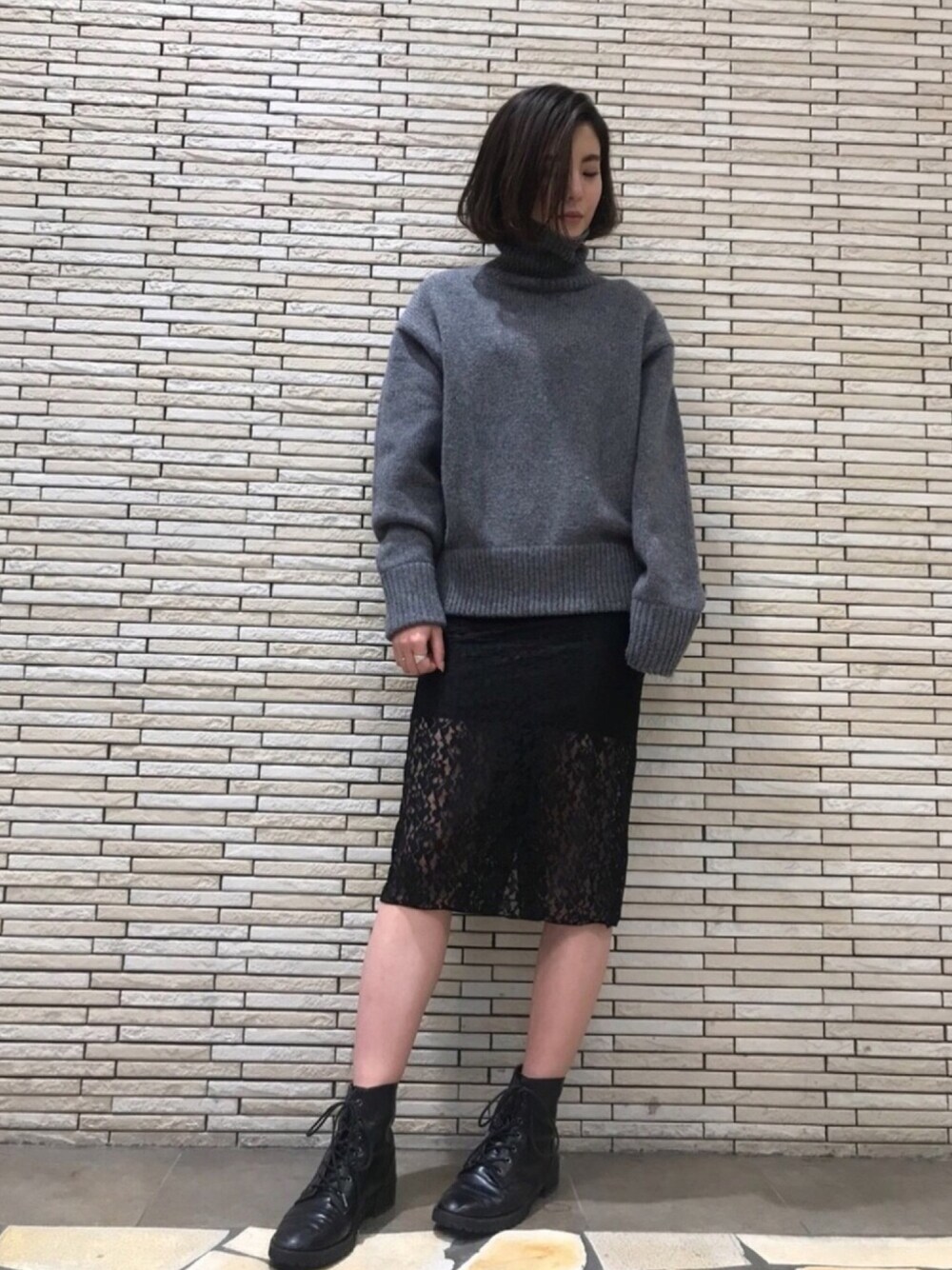 グレー系のニット/セーター、ブラック系のワンピース、ブラック系のブーツを着用したレディースの秋コーディネートの1枚目の写真