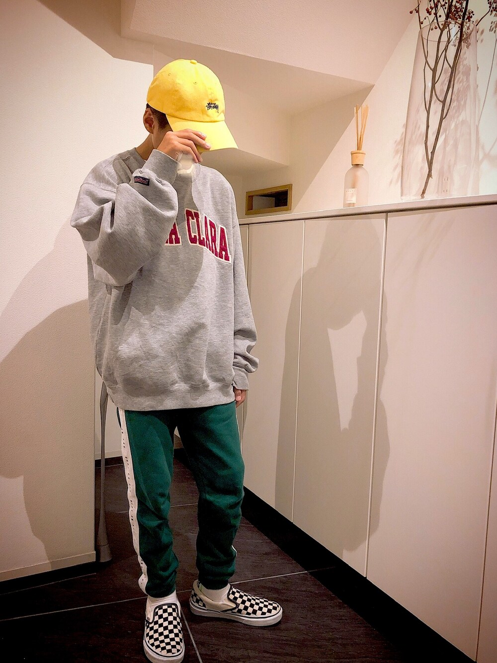 グレー系のスウェット、グリーン系のパンツ、ブラック系のスリッポンを着用したメンズの秋コーディネートの1枚目の写真