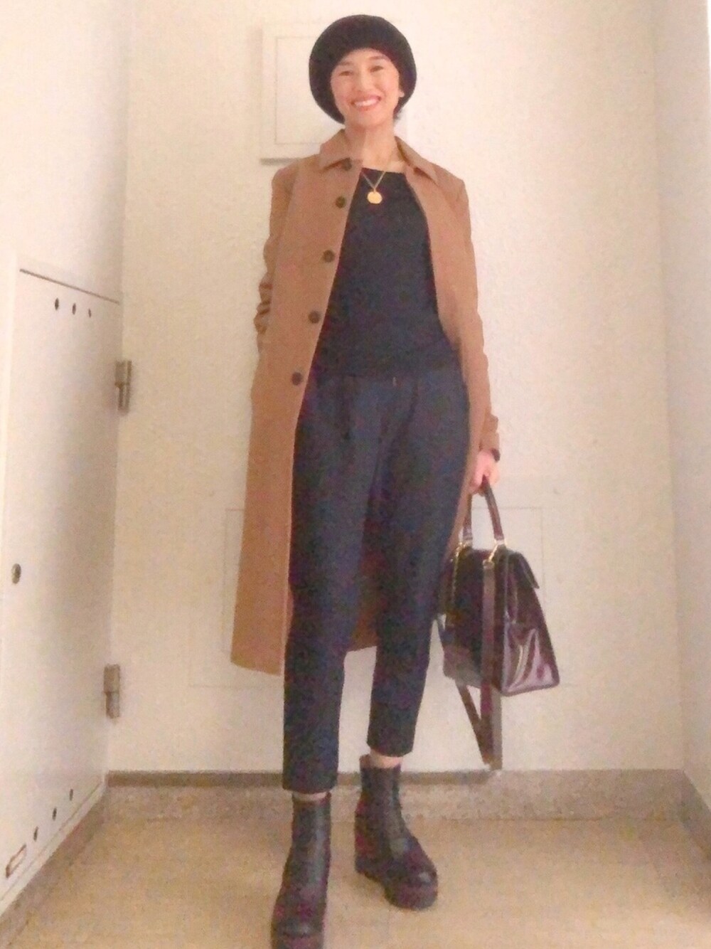 ブラウン系のハンドバッグ、ブルー系のTシャツ/カットソー、ブラック系のブーツを着用したレディースの春コーディネートの1枚目の写真