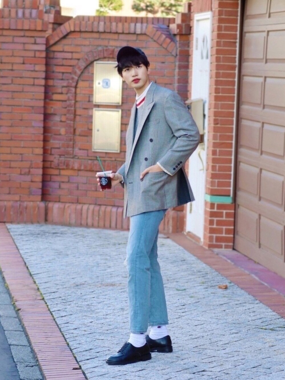 グレー系のニット/セーター、ブルー系のデニムパンツ、ブラック系のドレスシューズを着用したメンズの秋コーディネートの1枚目の写真