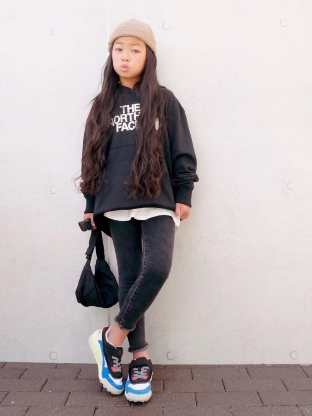 ブラック系のスウェット、ベージュ系のタンクトップ、ブラック系のパンツを着用したキッズの秋コーディネートの1枚目の写真