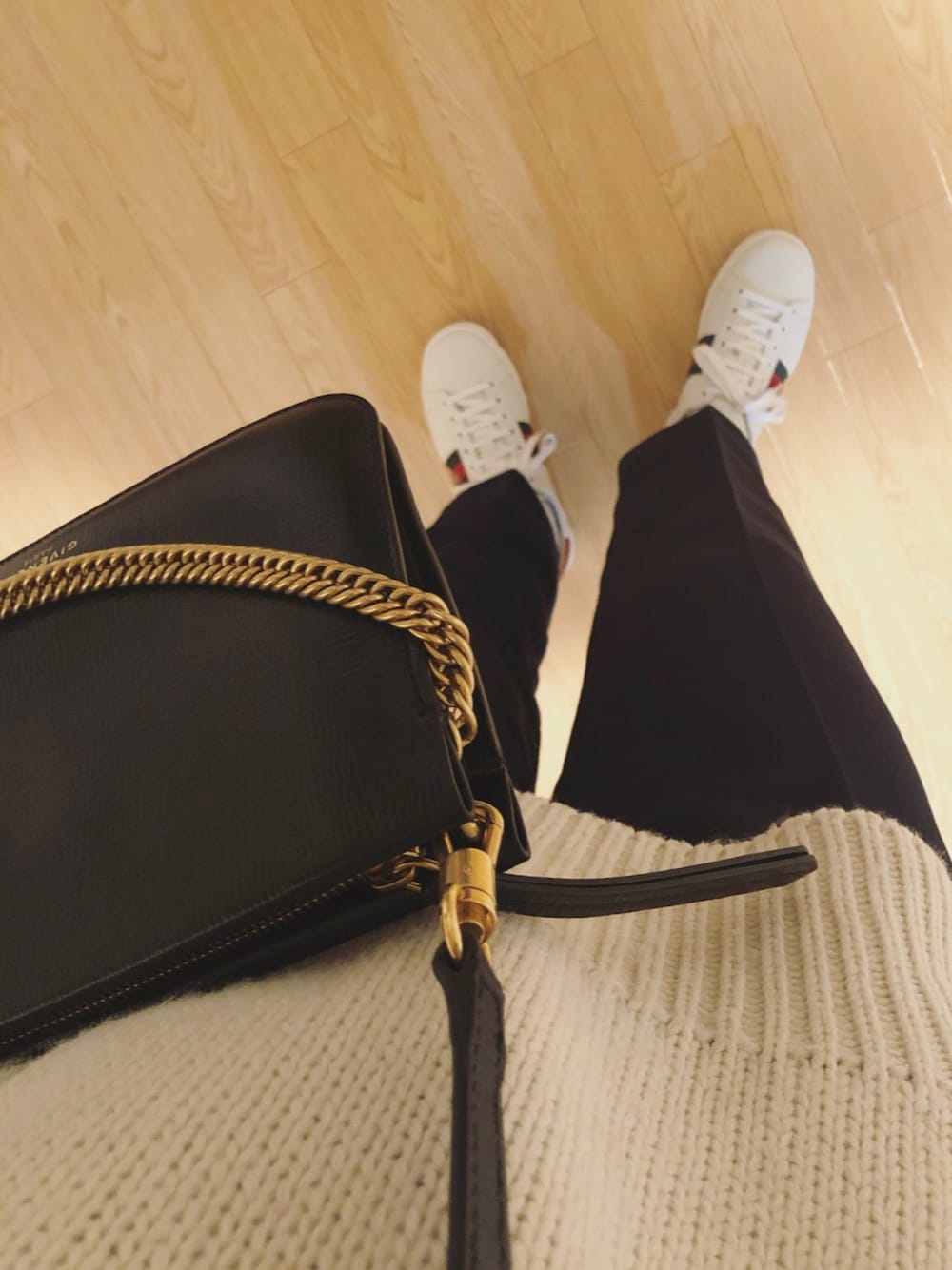 ホワイト系のスニーカー、ブラック系のショルダーバッグ、ベージュ系のニット/セーターを着用したレディースの冬コーディネートの1枚目の写真