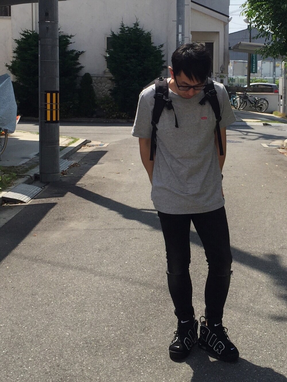ブラック系のバックパック/リュック、グレー系のTシャツ/カットソー、ブラック系のデニムパンツを着用したメンズの春コーディネートの1枚目の写真
