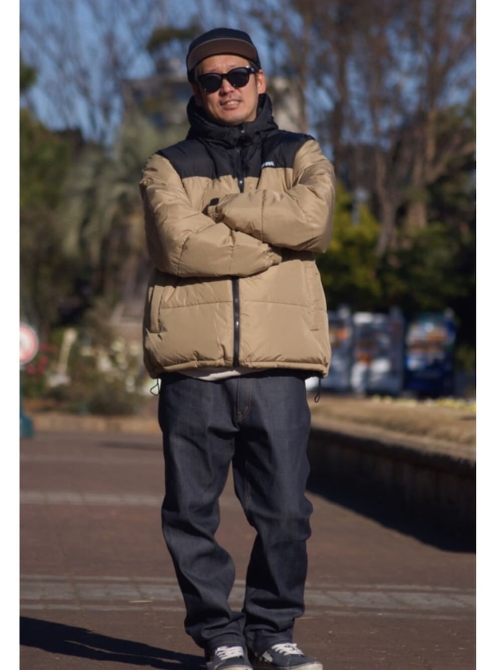 ブルー系のスニーカー、ブルー系のデニムパンツ、ベージュ系のダウンジャケット/コートを着用したメンズの冬コーディネートの1枚目の写真