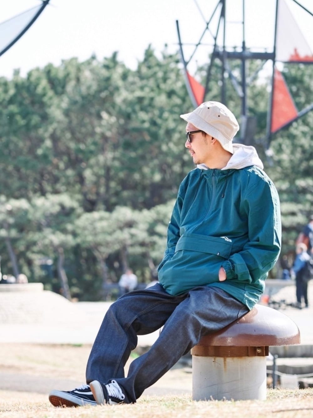 ブラック系のスニーカー、ブルー系のデニムパンツ、グリーン系のマウンテンパーカーを着用したメンズの春コーディネートの1枚目の写真