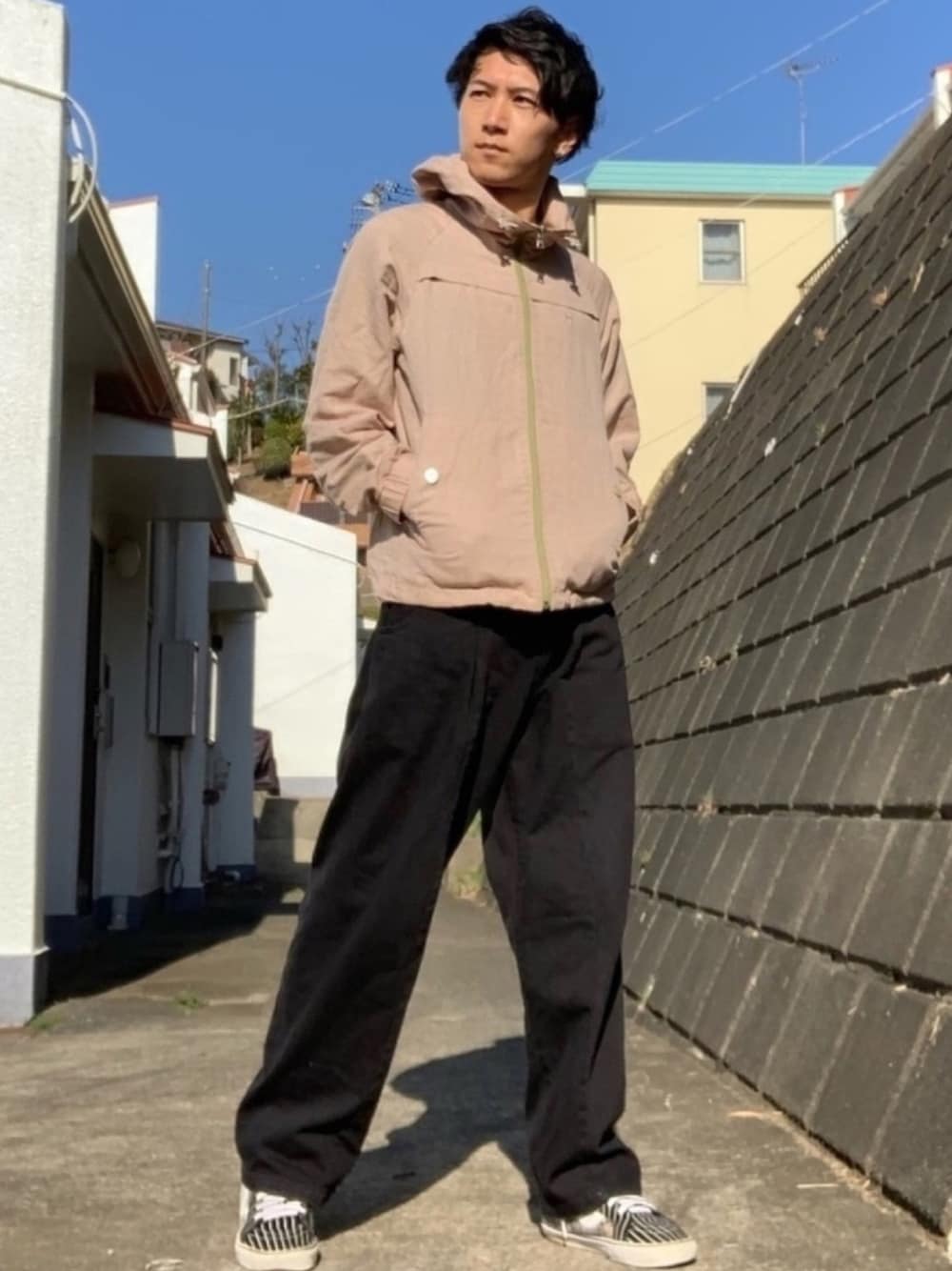 ブラック系のデニムパンツ、ブラック系のスニーカー、ベージュ系のパーカーを着用したメンズの春コーディネートの1枚目の写真