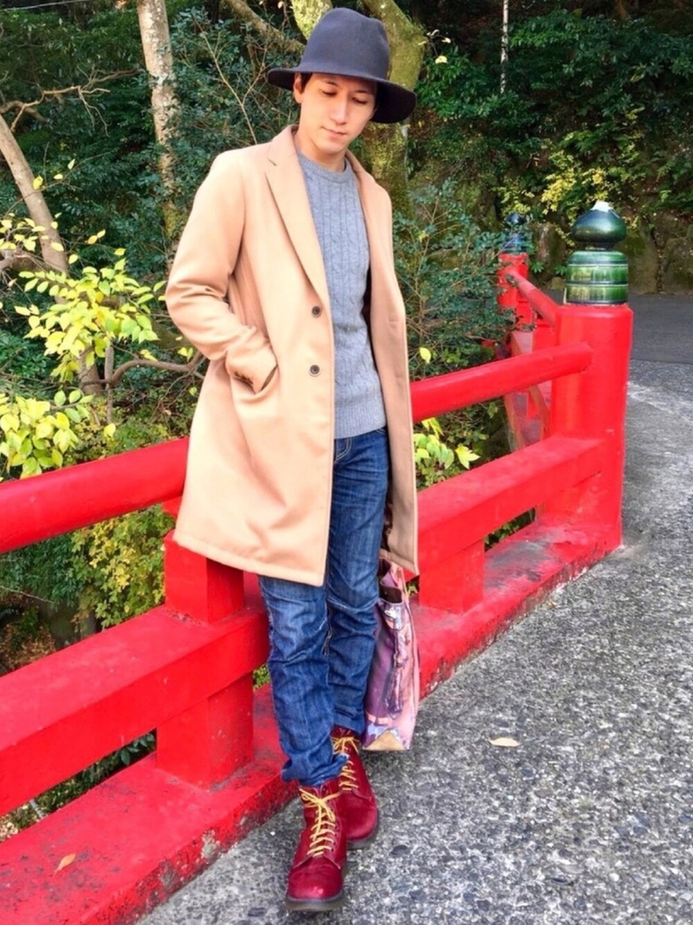 ベージュ系のチェスターコート、グレー系のニット/セーター、ブルー系のデニムパンツを着用したメンズの秋コーディネートの1枚目の写真